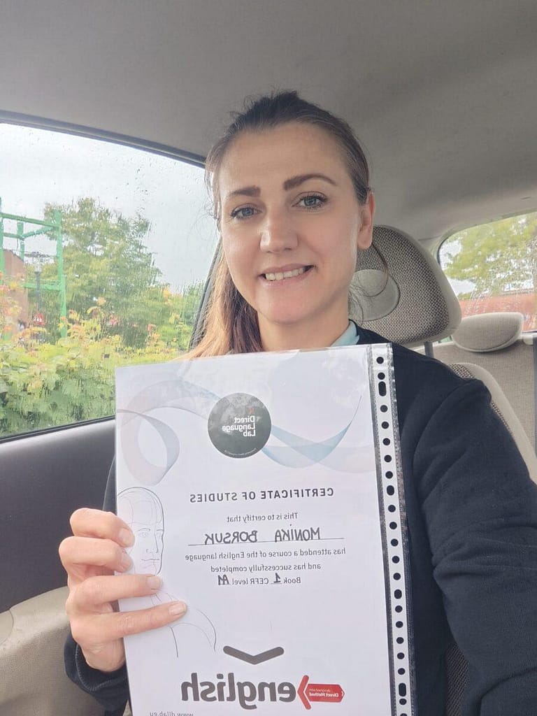 Monika z zespołu Pomocnik Holenderski prezentująca certyfikat ukończenia kursu językowego w samochodzie.